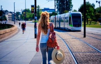 Femme marchant en pleine ville, face à un tramway dans une rue sans voiture